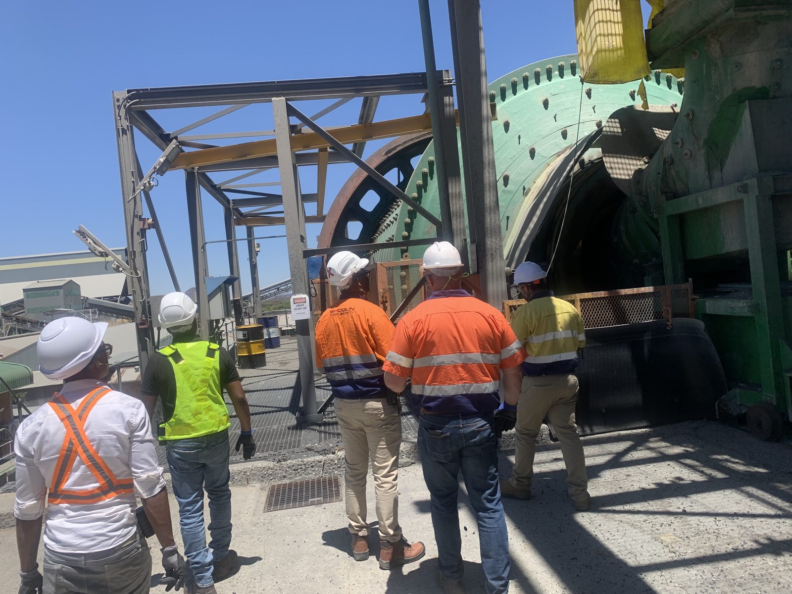 Team in PPE inspecting a grinding mill
